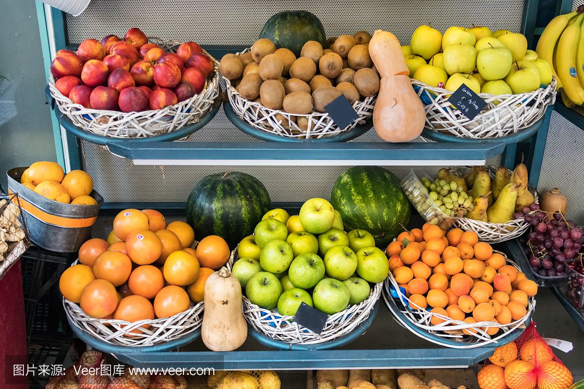 装着新鲜水果的篮子在户外的街边小摊上出售,苹果,桃子,猕猴桃和橙子。